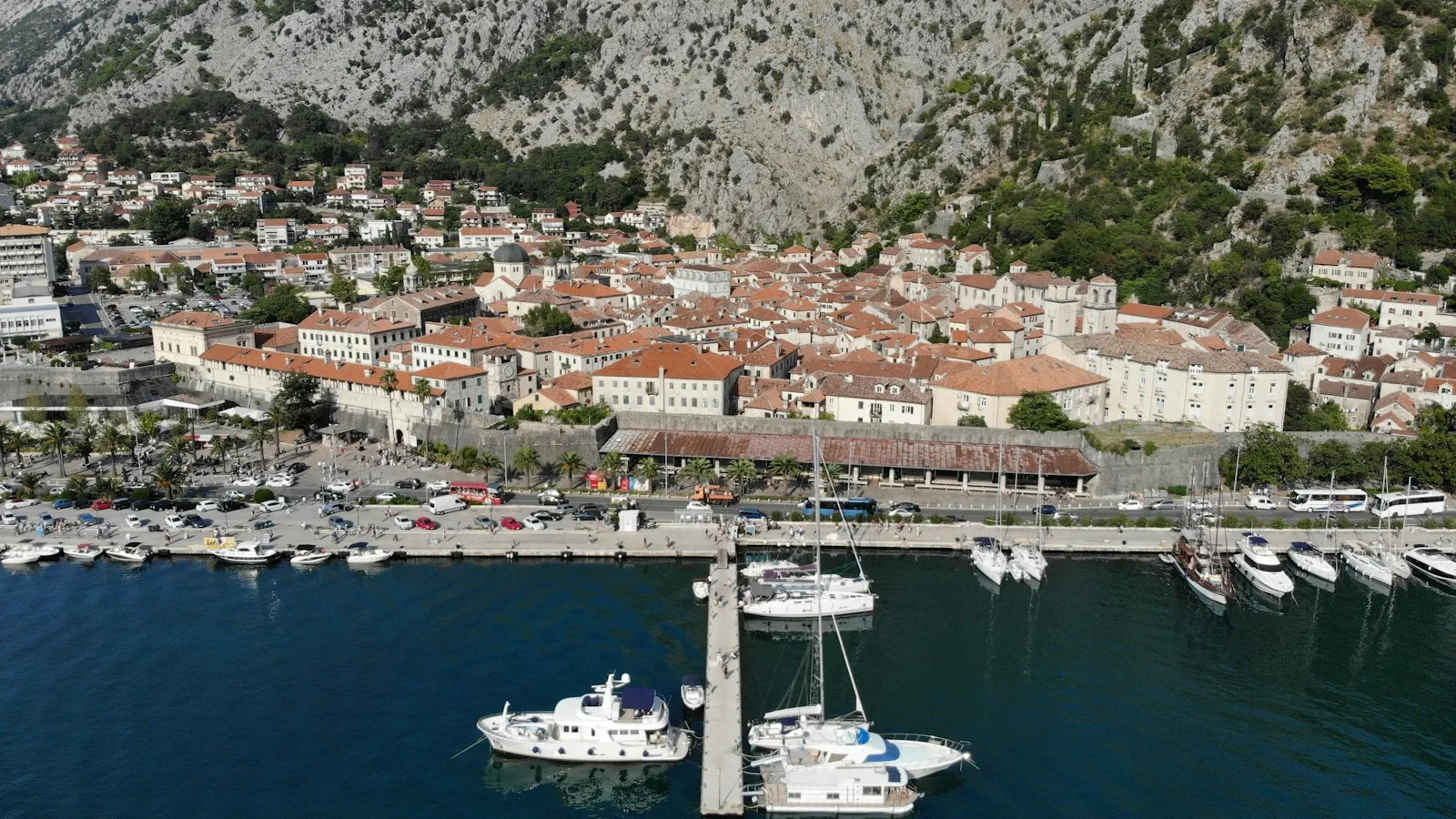 Rue côtière de Kotor avec voitures garées près d'un hôtel au bord de la baie
